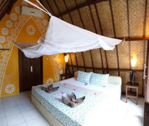 a bedroom with a bed with two cats on it at Rumah Cahaya in Gili Trawangan