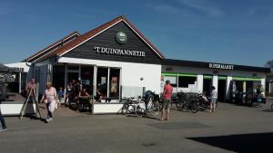 un grupo de personas parados fuera de una tienda en Strandcamping Valkenisse, en Biggekerke