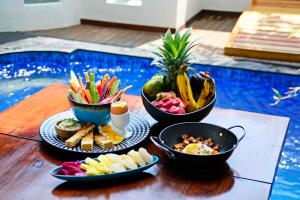 une table avec des assiettes de nourriture et des bols de fruits dans l'établissement Stay Shark Villas Gili Air, à Gili Air