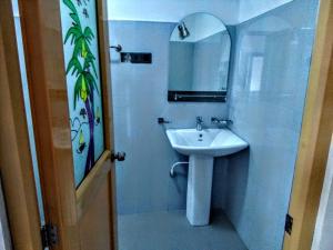 a white bathroom with a sink and a mirror at travellers nest inn in Nuwara Eliya
