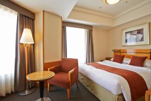 高松市にあるＪＲホテルクレメント高松のベッドと椅子付きのホテルルーム
