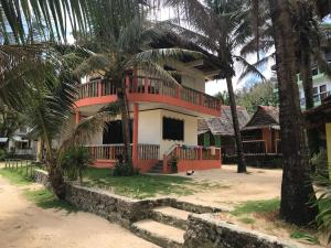 a house with a balcony and palm trees at Puraran Surf Beach Resort in Baras