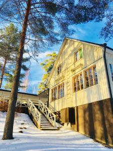 una casa di legno nella neve con un albero di Salonsaaren Lomakylä ad Asikkala