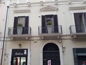 biały budynek z czarnymi okiennicami i drzwiami w obiekcie Cairoliapartment w mieście Bari