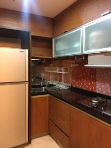 - une cuisine avec des placards en bois et un réfrigérateur blanc dans l'établissement Apartemen Braga City Walk, à Bandung