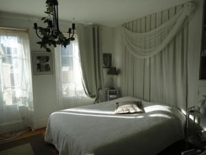a bedroom with a white bed and a chandelier at La Maison d'Hocquincourt in Bléneau