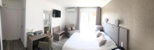 a bedroom with a bed and a desk and a chair at Le Galion Hotel et Restaurant Canet Plage - Logis in Canet-en-Roussillon