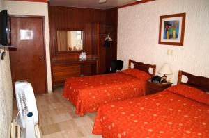 a hotel room with two beds and a television at Hotel Veracruz in Oaxaca City