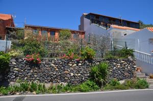 a stone retaining wall with flowers in front of a house at Rural Gomera in Arure