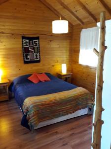 1 dormitorio con 1 cama en una cabaña de madera en Cabaña Rincón de Manzano en Villa La Angostura