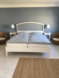 ein weißes Bett in einem Schlafzimmer mit 2 Tischen und 2 Lampen in der Unterkunft Nordseeperle Husum in Husum