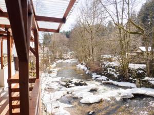 una vista invernale di un fiume da una casa di Haus am Fluss a Baiersbronn
