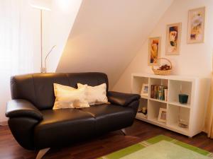 a black leather couch in a living room with a book shelf at Haus am Fluss in Baiersbronn