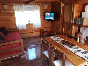 a dining room with a table and a television at Cabaña Rincón de Manzano in Villa La Angostura