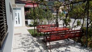 dwie czerwone ławki siedzące obok budynku w obiekcie Apartment and Rooms Markovic w mieście Senj