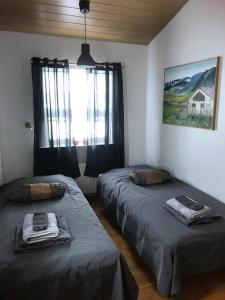 2 camas en una habitación con ventana en Eiði Farmhouse en Grundarfjordur