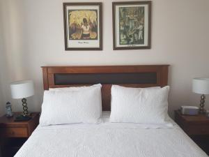 a bedroom with a bed with two pictures on the wall at Acogedor Departamento Vista al Mar in Antofagasta