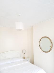 a white bedroom with a bed and a mirror at Llandudno holiday home in Llandudno