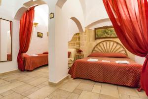 two beds in a room with red curtains at B&B Borgo San Martino in Monopoli