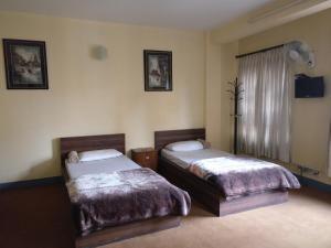 a hotel room with two beds and a window at Om Pension Guest House in Pātan