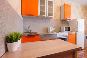 トムスクにあるАпартаменты на Савиныхのキッチン(オレンジ色のキャビネット、木製テーブル付)