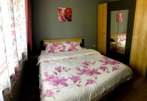 - une chambre avec un lit orné de fleurs roses dans l'établissement Radost, à Varna