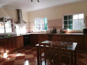 a kitchen with wooden cabinets and a table with chairs at Casa Maresia in Ponta do Sol