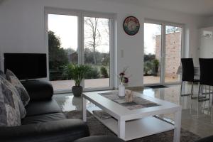 uma sala de estar com uma mesa de café branca e um relógio em Ferienhaus Westwind em Rhauderfehn