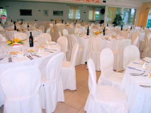 une salle remplie de tables et de chaises avec des nappes blanches dans l'établissement Fattoria Belvedere, à Bellaria-Igea Marina