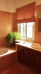a bathroom with a sink and a tub and a window at Quinta do Sotavento in Moncarapacho