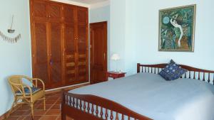 a bedroom with a large bed and a chair at Quinta do Sotavento in Moncarapacho