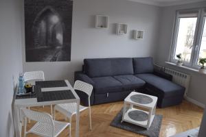 uma sala de estar com um sofá, uma mesa e cadeiras em Apartamenty Słowackiego 1 & Ogrodowa 2 em Sandomierz