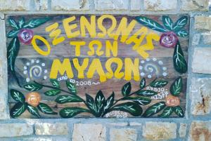 un cartel en una pared de ladrillo con flores. en O Xenonas Ton Mylon, en Míloi