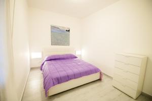 a white bedroom with a purple bed and a dresser at ArtHouse in San Vito lo Capo