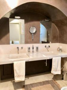 La salle de bains est pourvue de 2 lavabos et d'un grand miroir. dans l'établissement Palazzotto "Fasano Antica", à Fasano