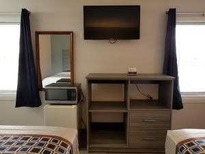 a bedroom with a television and a desk with a mirror at Old Bardstown Inn in Bardstown