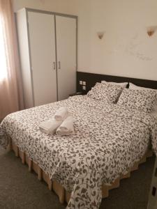 Galanopoulos Hotel في لوتراكي: غرفة نوم عليها سرير وعليها نعال بيضاء