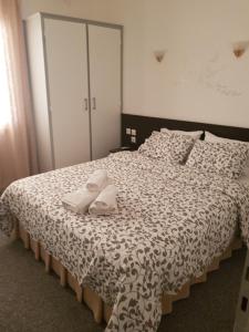 a bedroom with a bed with two white slippers on it at Galanopoulos Hotel in Loutraki