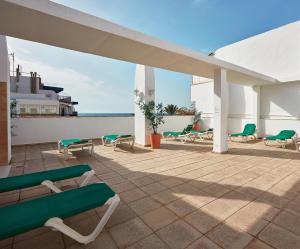 eine Terrasse mit Stühlen und Tischen auf dem Dach in der Unterkunft Aparthotel Milord's Suites in Benidorm