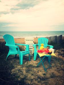two chairs and a table with food on the beach at LES PIEDS DANS L'EAU in Merville-Franceville-Plage