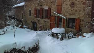 una casa con mesa y sillas en la nieve en La bergerie St Didier en Velay 43140 en Saint-Didier-en-Velay