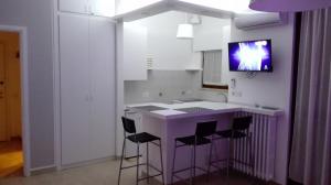 una cucina con isola viola e TV a parete di Mecenate Cozy Flat a Milano