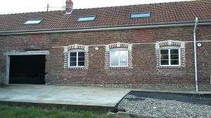 a brick building with a garage and a driveway at le clos du caribou in Beaumont-Hamel