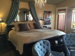 1 dormitorio con cama, silla y espejo en The Tuwanek Hotel and Spa, en Sechelt