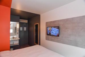 1 dormitorio con 1 cama y TV en la pared en ibis budget Saint Lô, en Saint Lo