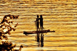 duas pessoas de pé numa prancha de padel na água em The Tuwanek Hotel and Spa em Sechelt