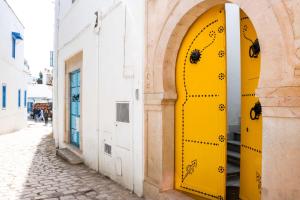 a yellow door on a building in a street at La Maison De L'artiste in Sidi Bou Saïd