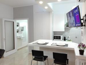 cocina blanca con encimera blanca y sillas en Mecenate Cozy Flat, en Milán