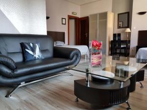 ein Wohnzimmer mit einem schwarzen Ledersofa und einem Glastisch in der Unterkunft Hôtel-Restaurant du Soleil Levant in Sarrebourg