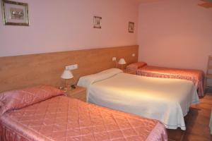 Habitación de hotel con 2 camas y 2 lámparas en Hostal Arévacos en Soria